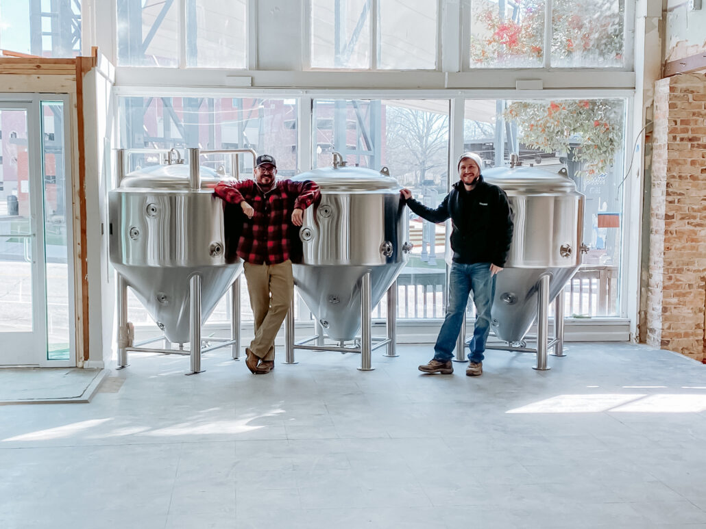 Alex and John standing next to their new brewing equipment.